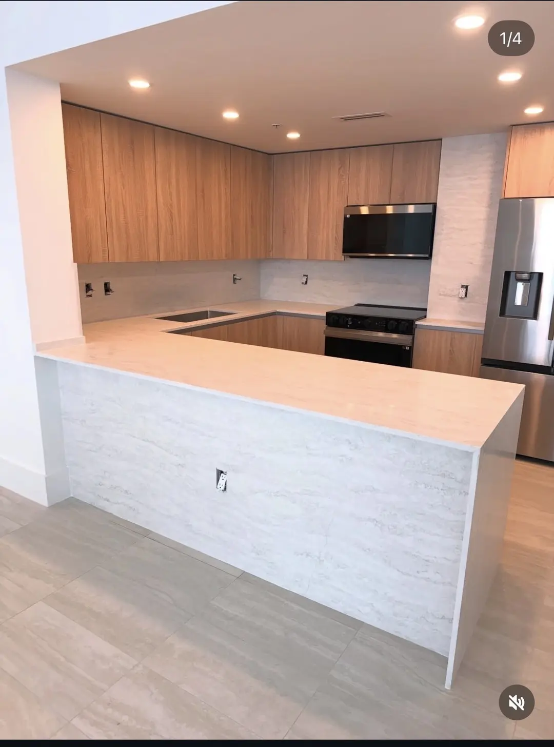 Kitchen with warm wood-grain cabinetry and a veined stone-look waterfall peninsula